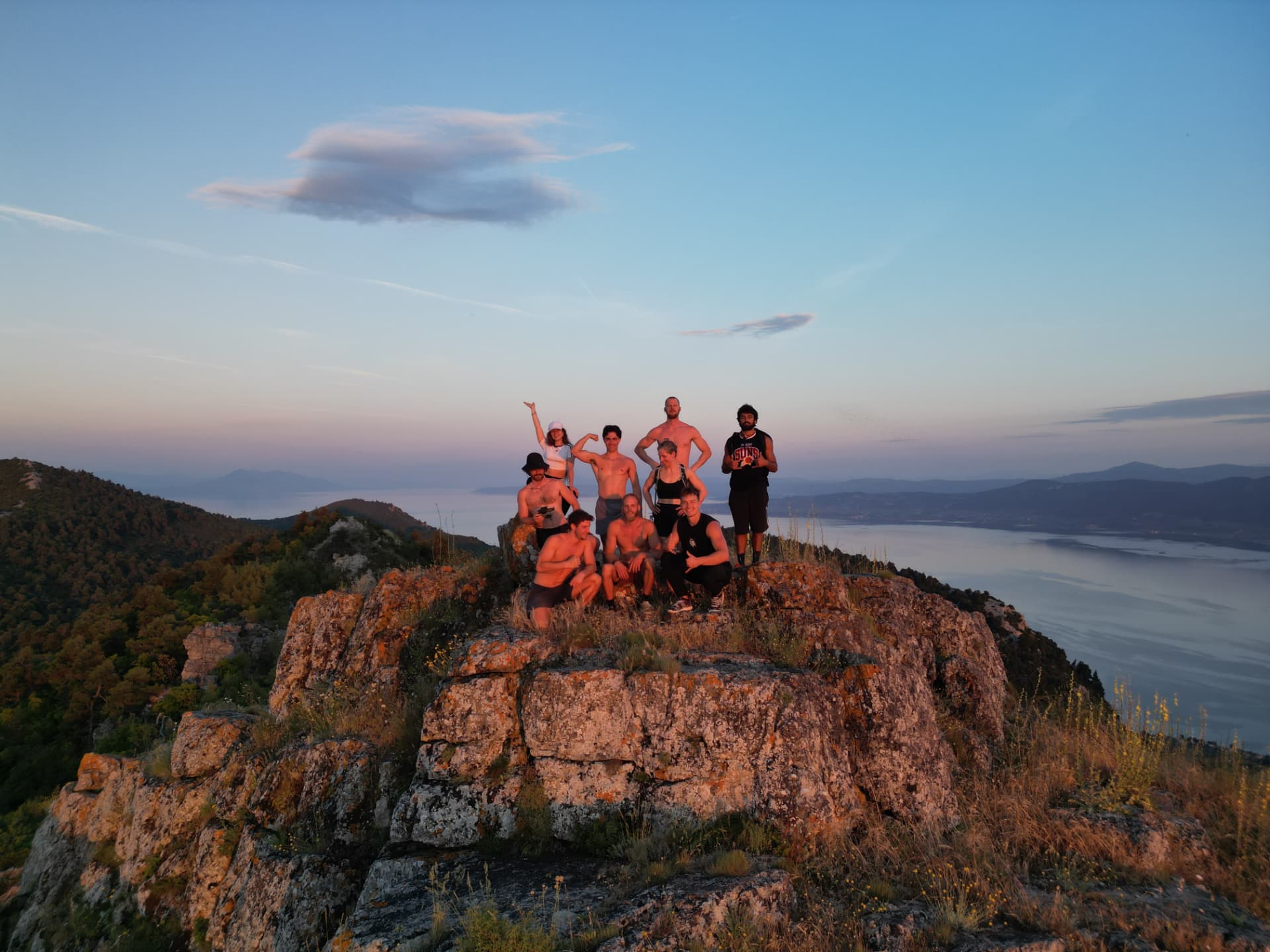 Group on a mountain summit at dusk above the sea